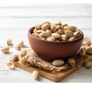 Bowl of salty roasted pista on wooden table for healthy snacking